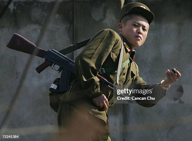 North Korean soldier picks up a stone to throw at photographers on the banks of the Yalu River in the North Korean town of Sinuiju, opposite the...