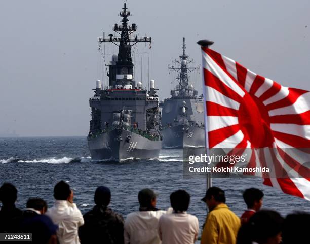 Spectators watch a parade of ships as the Japanese Maritime Self-Defense Force sails in formation during a naval fleet review exercises on October...