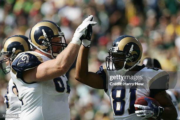 Wide receiver Torry Holt of the St. Louis Rams high fives offensive guard Adam Timmerman during the game against the the Green Bay Packers at Lambeau...