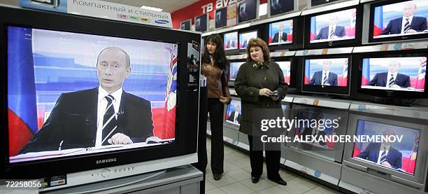 Moscow, RUSSIAN FEDERATION: Customers look at Russian President Putin on TV screens in a shop 25 October 2006 in Moscow, as President Vladimir Putin...