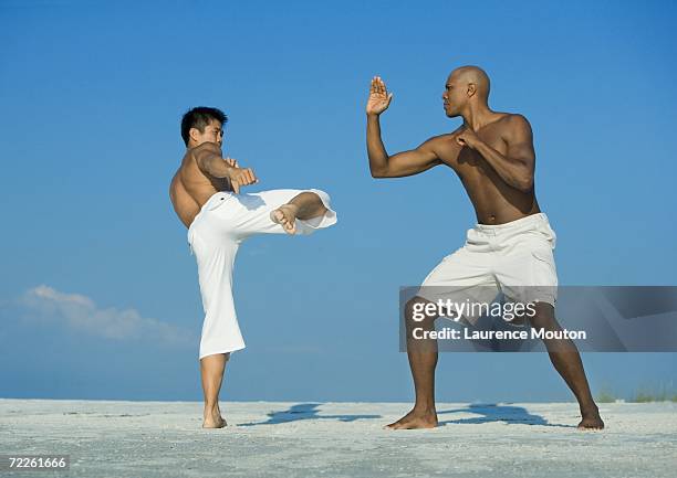 two men practicing martial arts on beach - black shorts stockfoto's en -beelden