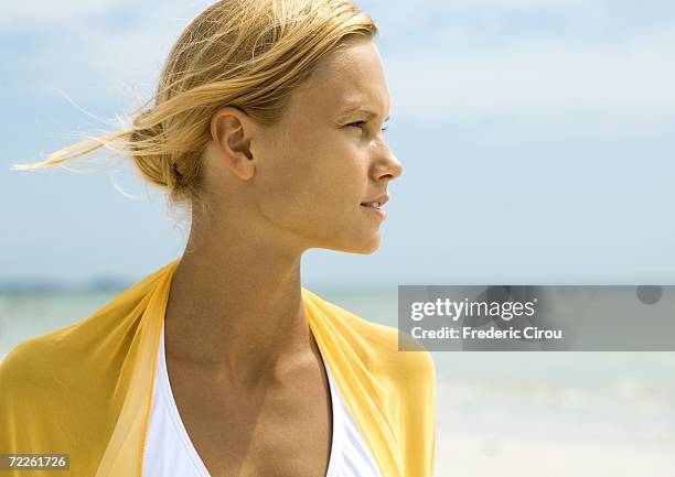 woman standing in sun on beach, looking to distance - squinting stock pictures, royalty-free photos & images