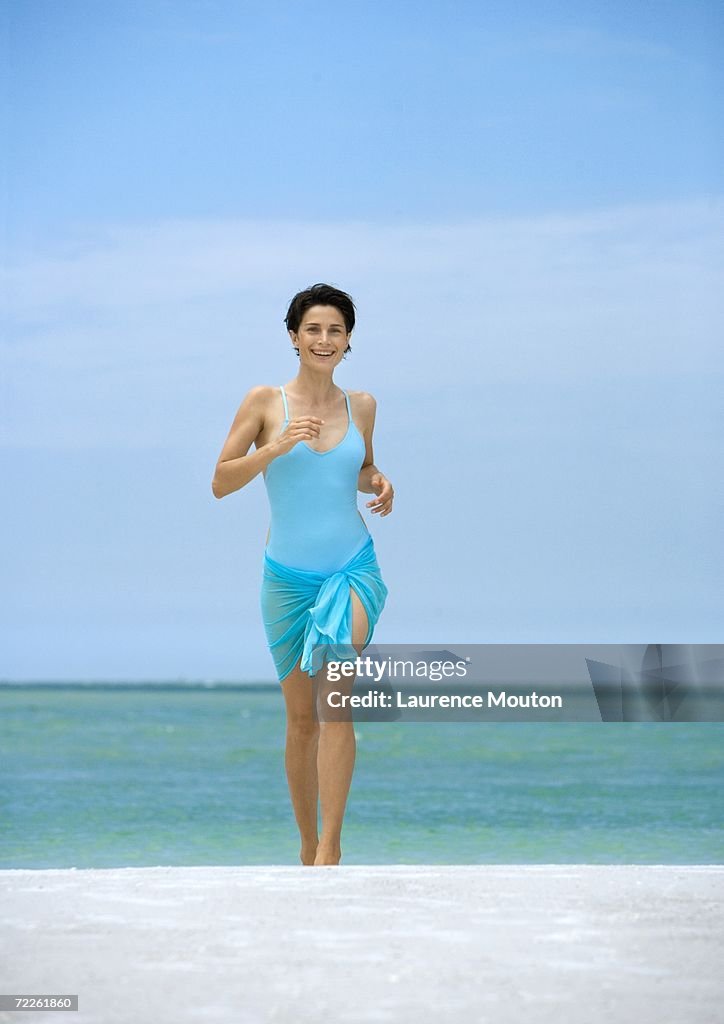 Woman running on beach, front view