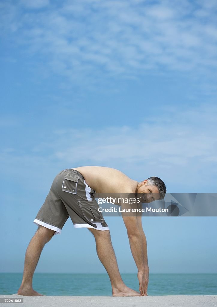 Man doing stretches on beach