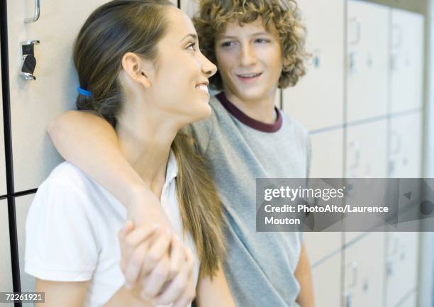 teen couple leaning against school lockers - young love stock-fotos und bilder