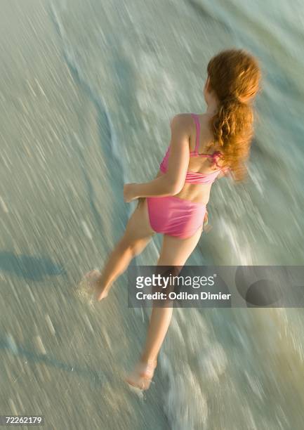 girl running in surf - tween girl swimsuit stock-fotos und bilder