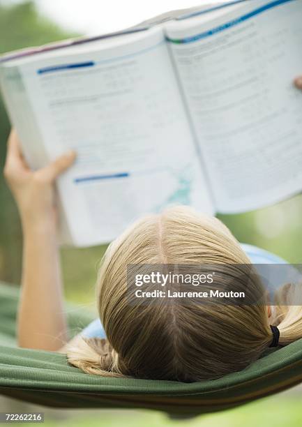 girl reading school book on hammock - hair parting stockfoto's en -beelden