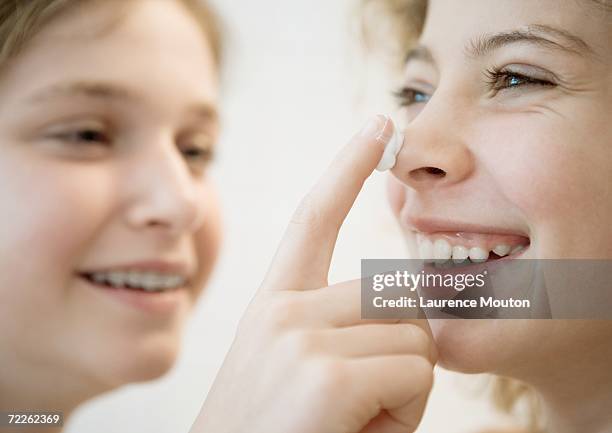 girl putting lotion on friend's nose - 人間の鼻 ストックフォトと画像