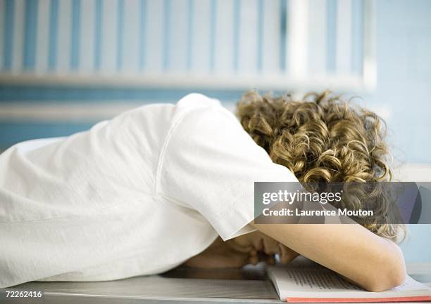 teen boy with head down on school book - sólo-una-adolescente fotografías e imágenes de stock