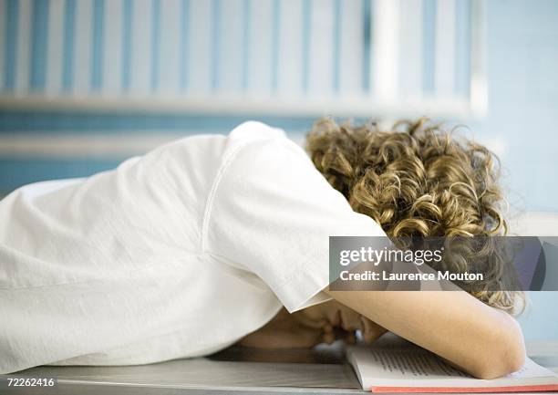 teen boy with head down on school book - one teenage boy only fotografías e imágenes de stock