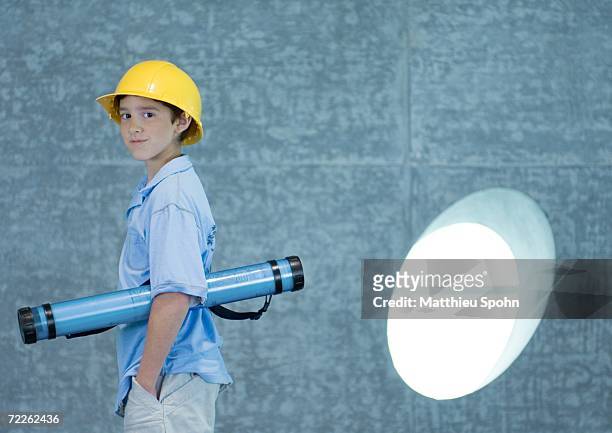 boy holding document tube under arm and wearing hard hat - boy in hard hat photos et images de collection