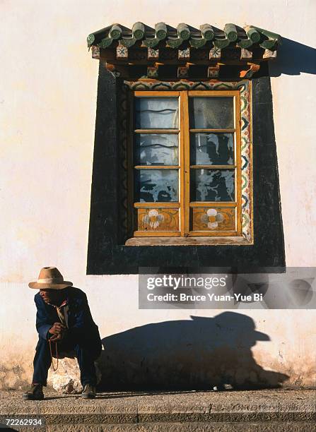 tibetan pilgrim takes short break outside songzanlin monastery, zhongdian, china - songzanlin monastery stock-fotos und bilder