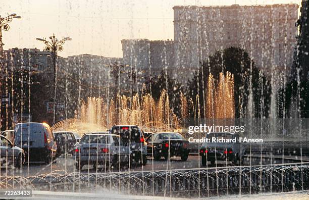 palace of parliament, traffic and fountain, unirri square, bucharest, romania - bucharest parliament stock pictures, royalty-free photos & images