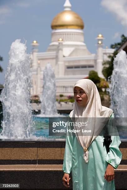 muslim woman with mosque in background, omar ali saifuddien mosque, brunei darussalam, bandar seri begwan, brunei - omar ali saifuddin mosque stock pictures, royalty-free photos & images