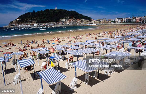 striped sunshades at playa de la concha with mt urgull in background, san sebastian, spain - playa de la concha fotografías e imágenes de stock