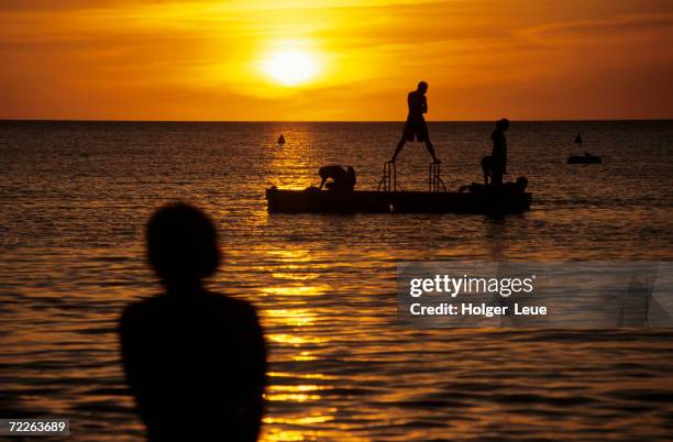 people on pontoon silhouetted at sunset, noumea, new caledonia - grande terre nueva caledonia fotografías e imágenes de stock