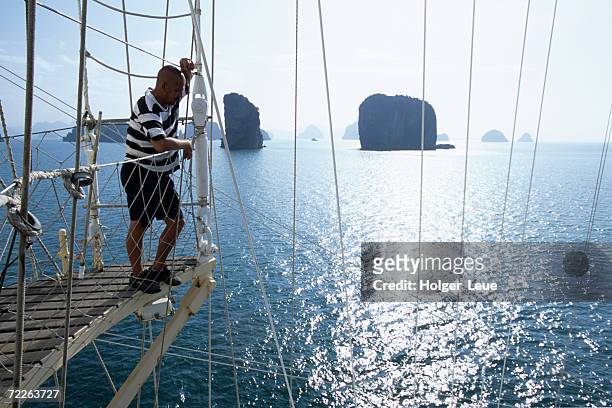 man on star flyer mast overlooking water, phang-nga bay, thailand - star flyer stock pictures, royalty-free photos & images