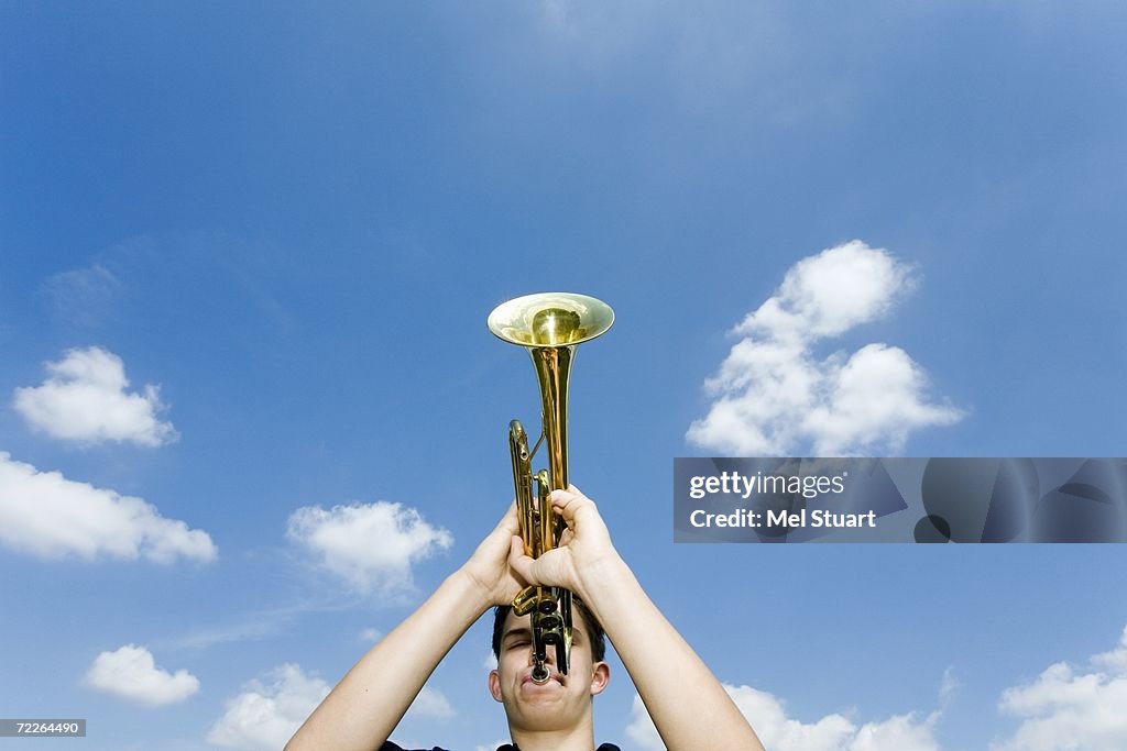 Young man playing trumpet, low angle view