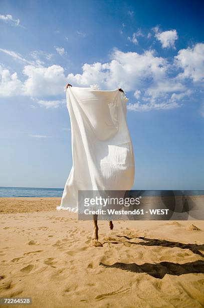 young woman hiding behind bath towel on beach - towel stock pictures, royalty-free photos & images