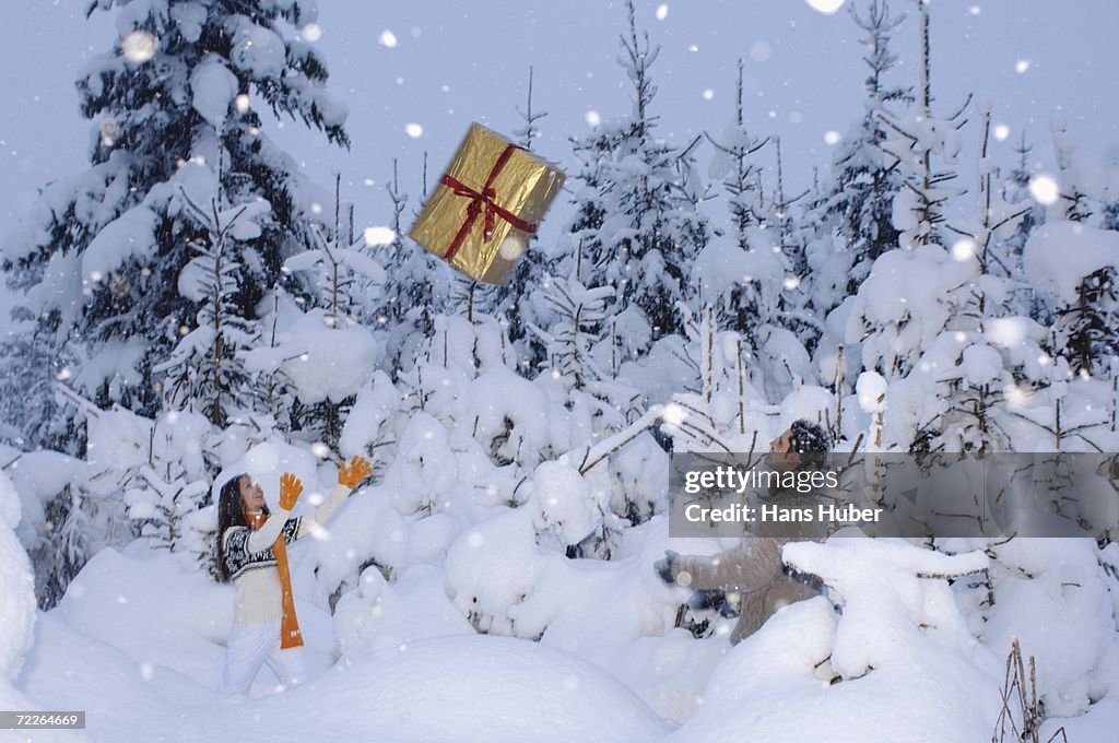 Couple in snow throwing gift at each other