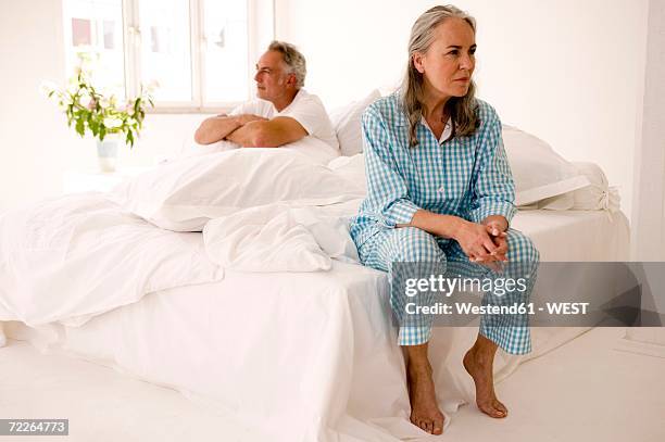 mature couple sitting on bed (focus on woman in foreground) - contemplation couple stock pictures, royalty-free photos & images