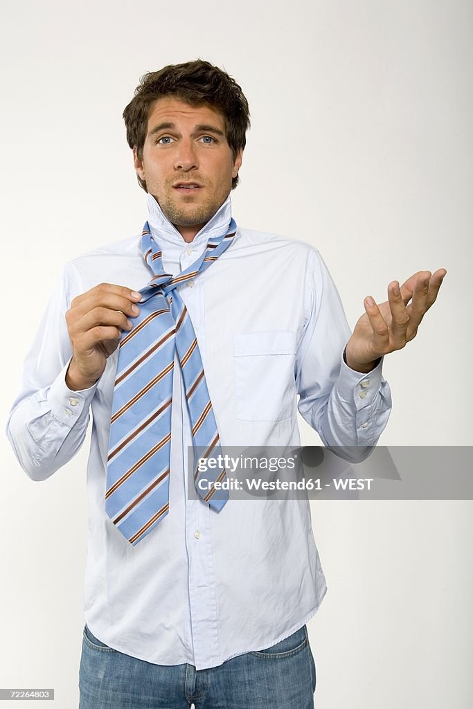 Young businessman getting ready, adjusting tie, close-up, portrait