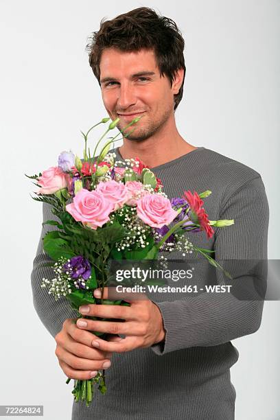 young man holding bouquet of flowers, smiling, close-up, portrait - man giving flowers stock pictures, royalty-free photos & images