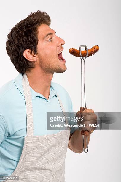 young man holding grilled sausage, close up - mouth open eating stock pictures, royalty-free photos & images