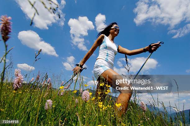young woman nordic walking in meadow, germany, low angle view - nordic walking stock pictures, royalty-free photos & images