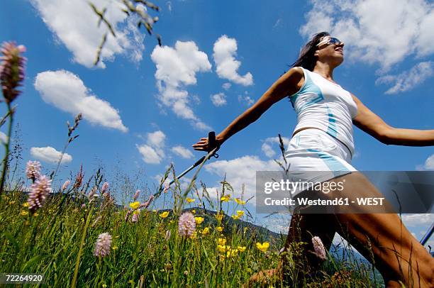 young woman nordic walking in meadow, germany, low angle view - ski pole stock pictures, royalty-free photos & images