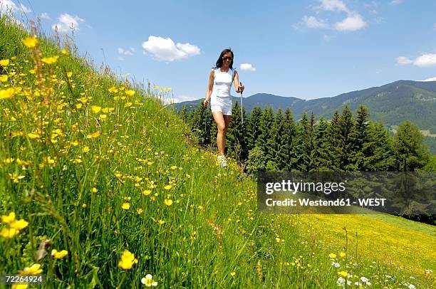 young woman walking with ski pole in meadow - hiking pole stock-fotos und bilder