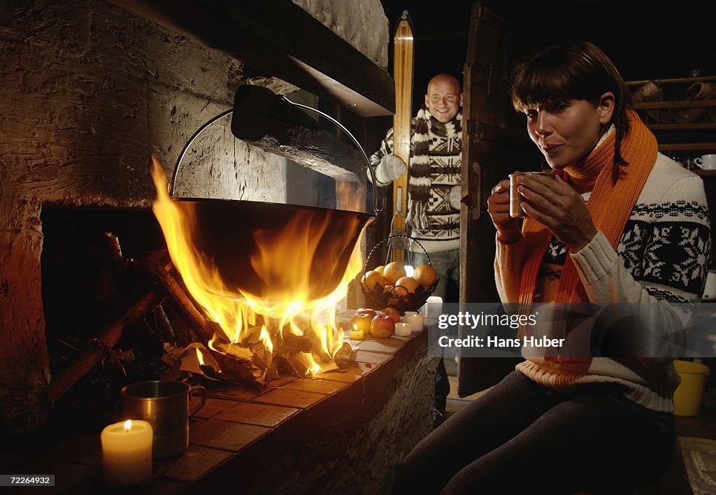 Man looking at woman sitting by fireplace