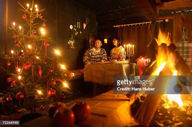 couple sitting at table in alpine hut looking at christmas tree - candle holder stock pictures, royalty-free photos & images