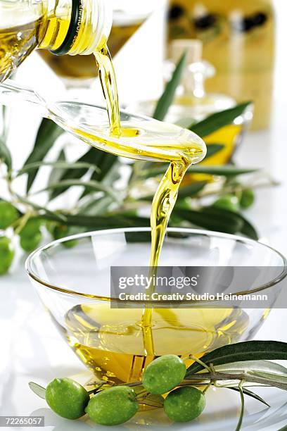 fresh green olives and olive oil in glass bowl - olijfolie stockfoto's en -beelden