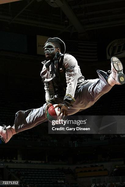 An acrobat, dressed in a Halloween costume, dunks the ball during an intermission in the preseason game between the Milwaukee Bucks and the Denver...