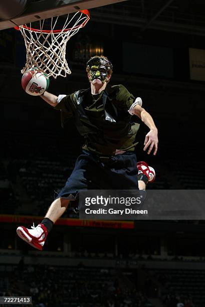 An acrobat, dressed in a Halloween costume, dunks the ball during an intermission in the preseason game between the Milwaukee Bucks and the Denver...