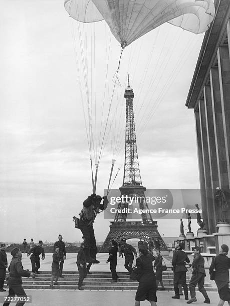 Parachutist suspended from a crane lands on the terrace of the Palais de Chaillot near The Eiffel Tower, Paris, during the making of a film set in...