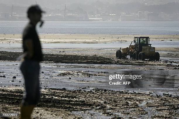 Workers drive bulldozers to clean un the debris washed down by heavy rains near the village of Poio, 27 October 2006. In what has been a particularly...