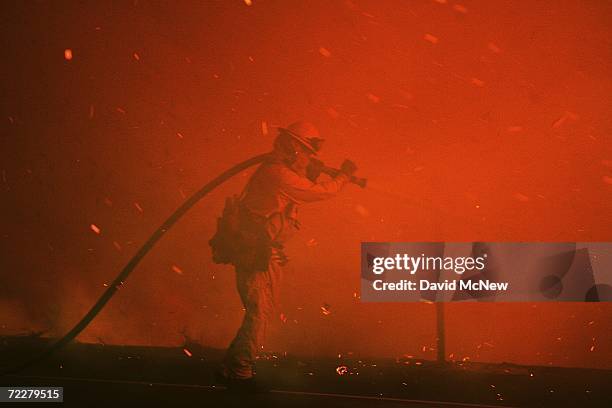 Embers blow around a firefighter battling the deadly Esperanza Fire before dawn in the San Jacinto Mountains on October 27, 2006 near Banning,...
