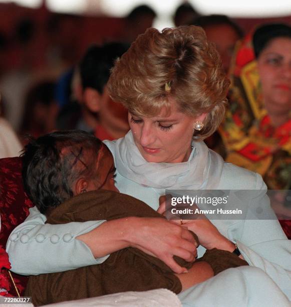 Diana, Princess of Wales, wearing a pale blue shalwar kameez, cradles a young Cancer patient in her arms during a visit to Shaukat Khanum Hospital on...