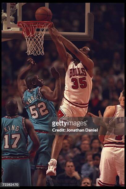 Forward Jason Caffrey of the Chicago Bulls drops the ball into the hoop above defending center Eric Mobley of the Vancouver Grizzlies at the United...