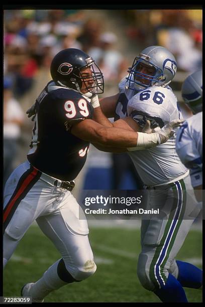 Defensive lineman Dan Hampton of the Chicago Bears and offensive lineman Andy Heck of the Seattle Seahawks tangle up during a game at the Kingdome in...