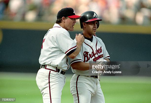 Third base coach Ned Yost of the Atlanta Braves congratulates Bret Boone on his triple base hit during the game against the Houston Astros at Turner...