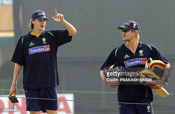 Australian cricketer Shane Watson listens to teammate Nathan Bracken as they arrive for a training session at the Punjab Cricket Association stadium...