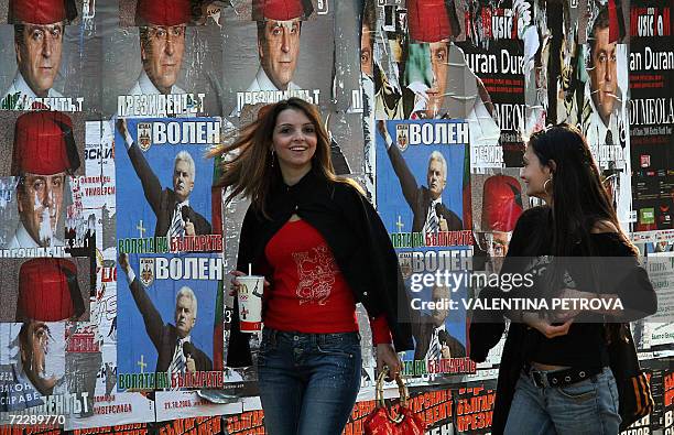 Bulgarian girls laugh at caricatures of election posters of incumbent Socialist President Georgy Parvanov "wearing" a Turkish fez, and...