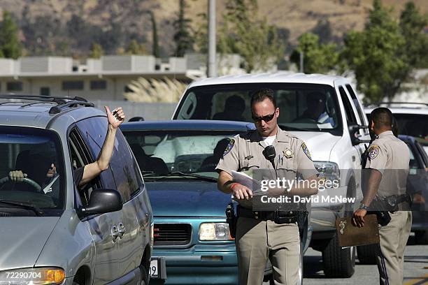 Driver gestures after police give him permission to pass as residents line up to be allowed to return to their homes for the first time since the...