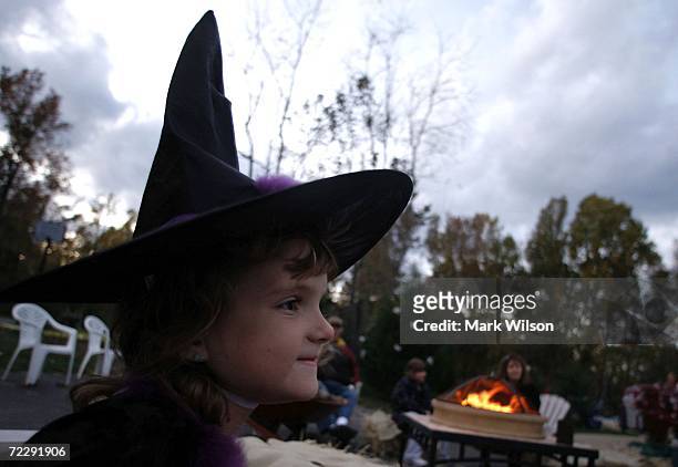 Year-old Ellie Price, who is dressed as a witch, stands near camp fire during a Halloween party October 28, 2006 in Huntingtown, Maryland. Halloween...