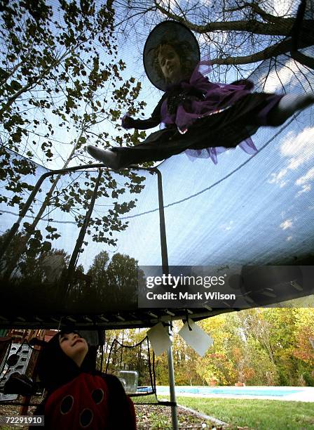 Year-old Madison Rose who is dressed as a lady bug watches as 6 year-old Ellie Price who is dressed as a Witch jumps on a trampoline during a...