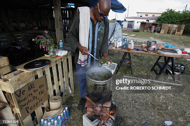 Jonathan, a homeless man who says has been living in the streets for 16 years, serves himself a plate of cooked greens near a makeshift kitchen they...