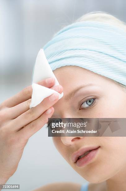 young woman face using a cleansing cotton on her forehead, close-up (studio) - baby wipes stock pictures, royalty-free photos & images